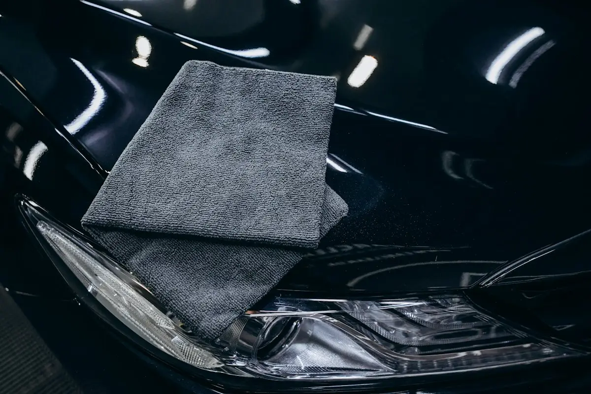 Microfiber towel wiping a glossy car hood